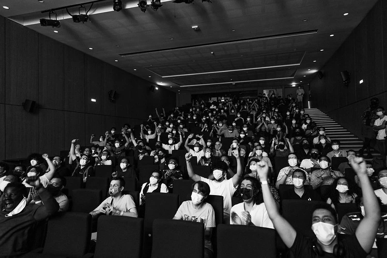 une photo en noir et blanc d'une public dans un amphitheatre qui encourage des joueurs