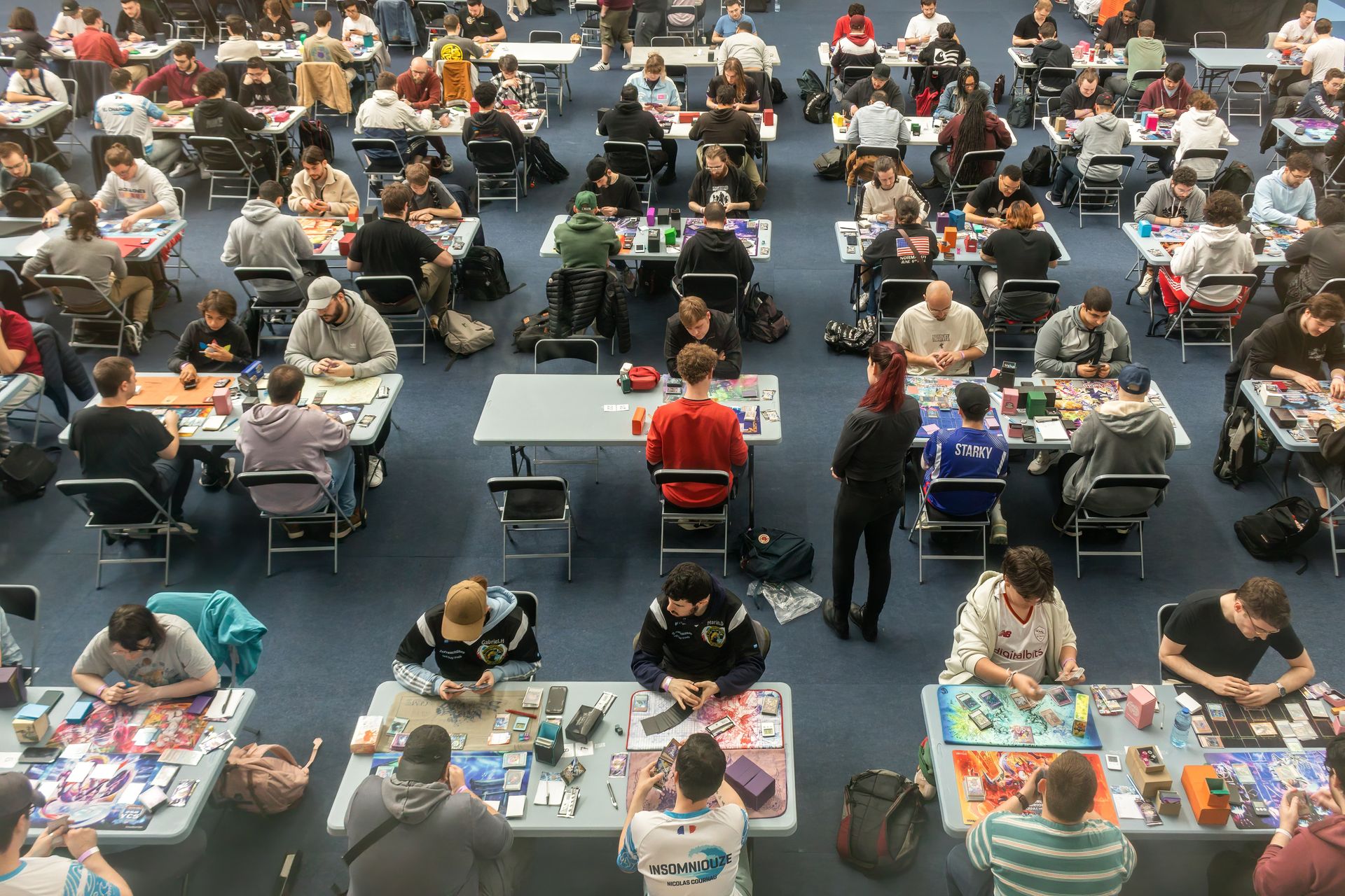 de nombreuses tables avec des joueurs de yu gi oh en plein tournoi