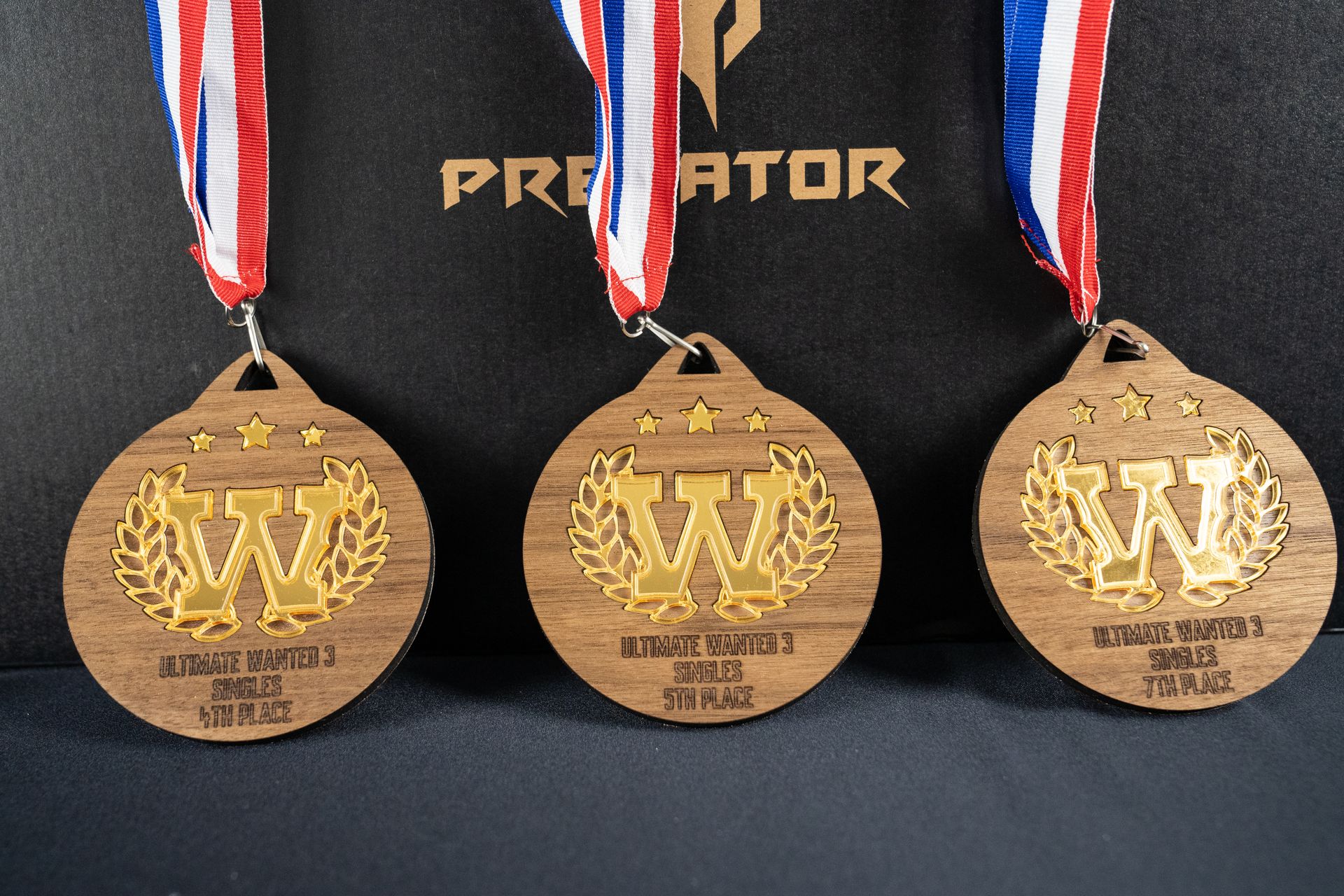 3 médailles en bois avec le logo wanted en or pour ultimate wanted 3