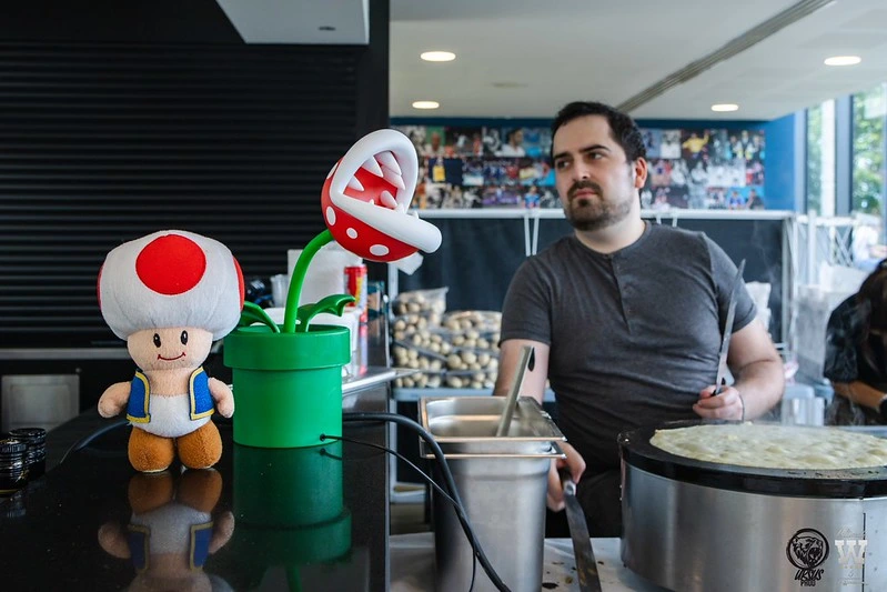 champi qui fait des crèpes sur son stand avec une peluche toad et une plante piranah